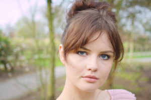 Blogger with blue eyes wearing hair in messy bun style