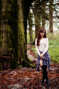 Teen blogging photographed in woodland setting wearing plaid shirt
