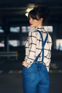 Teen wearing cream and black plaid shirt with cross back dungarees