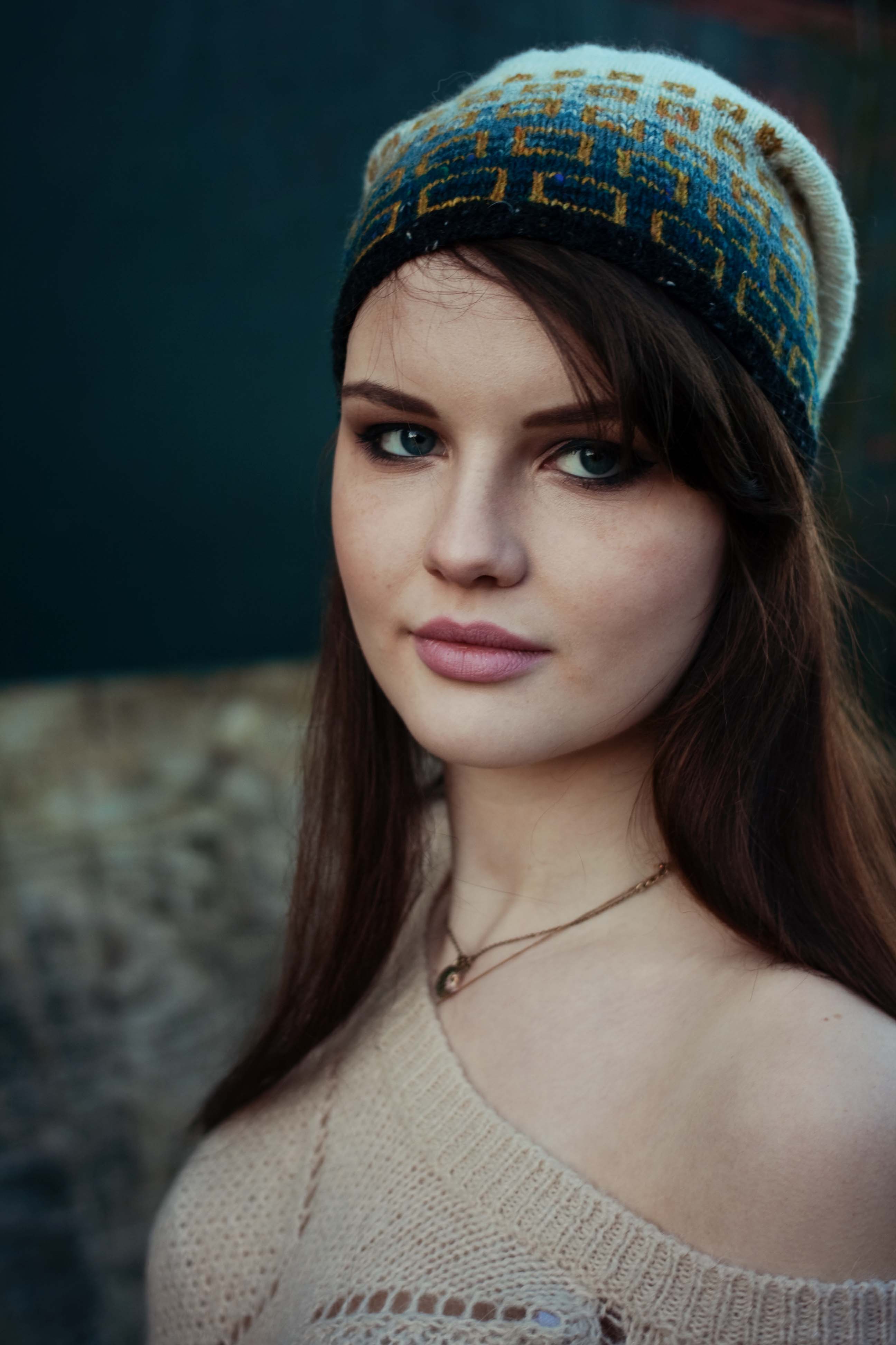 Brunette wearing neutral lipstick and handknit ombre hat