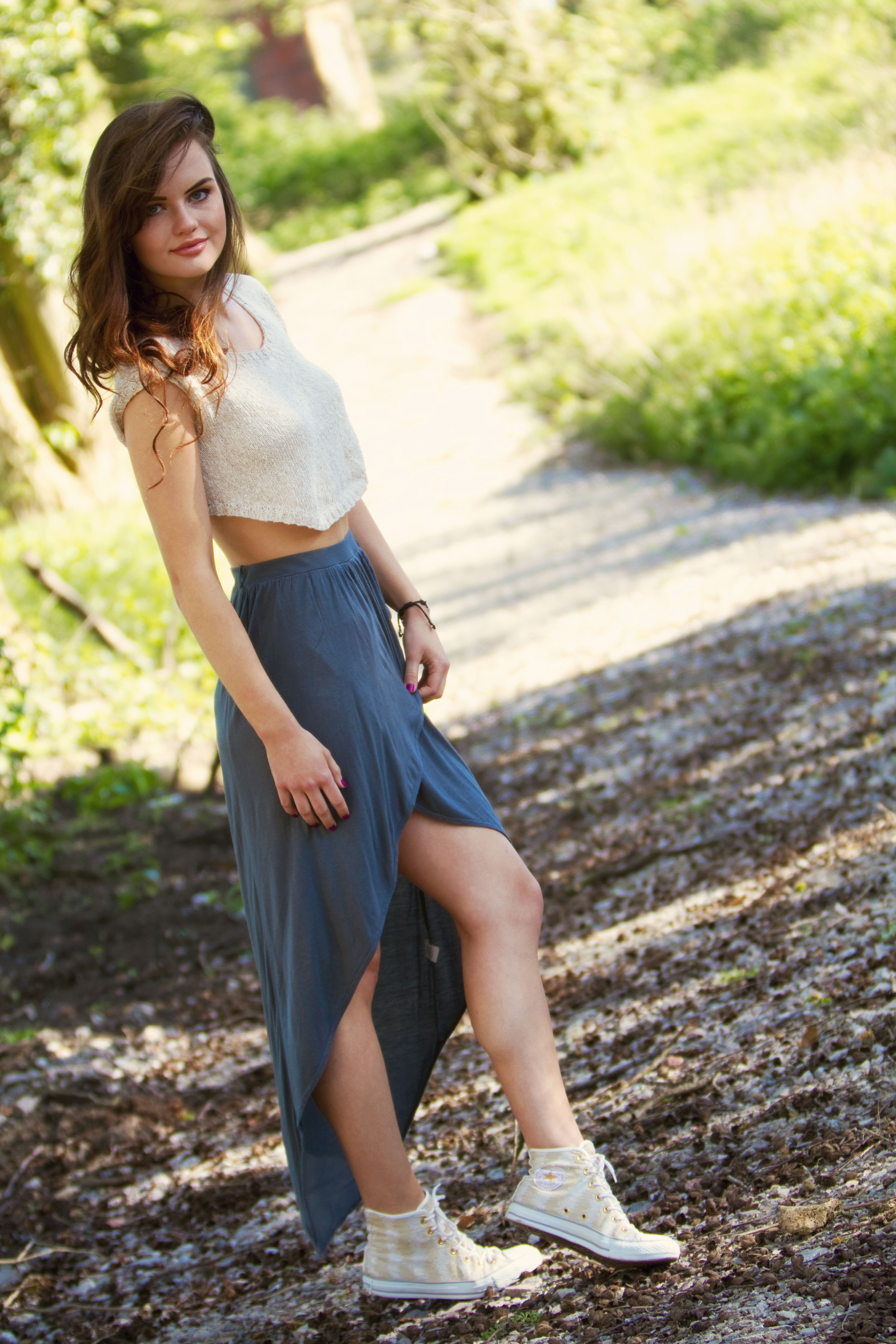 Teen girl wearing grey and cream outfit on woodland path