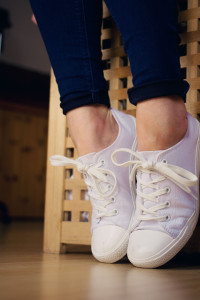 Girl wearing white lace up plimsolls and dark blue skinny jeans