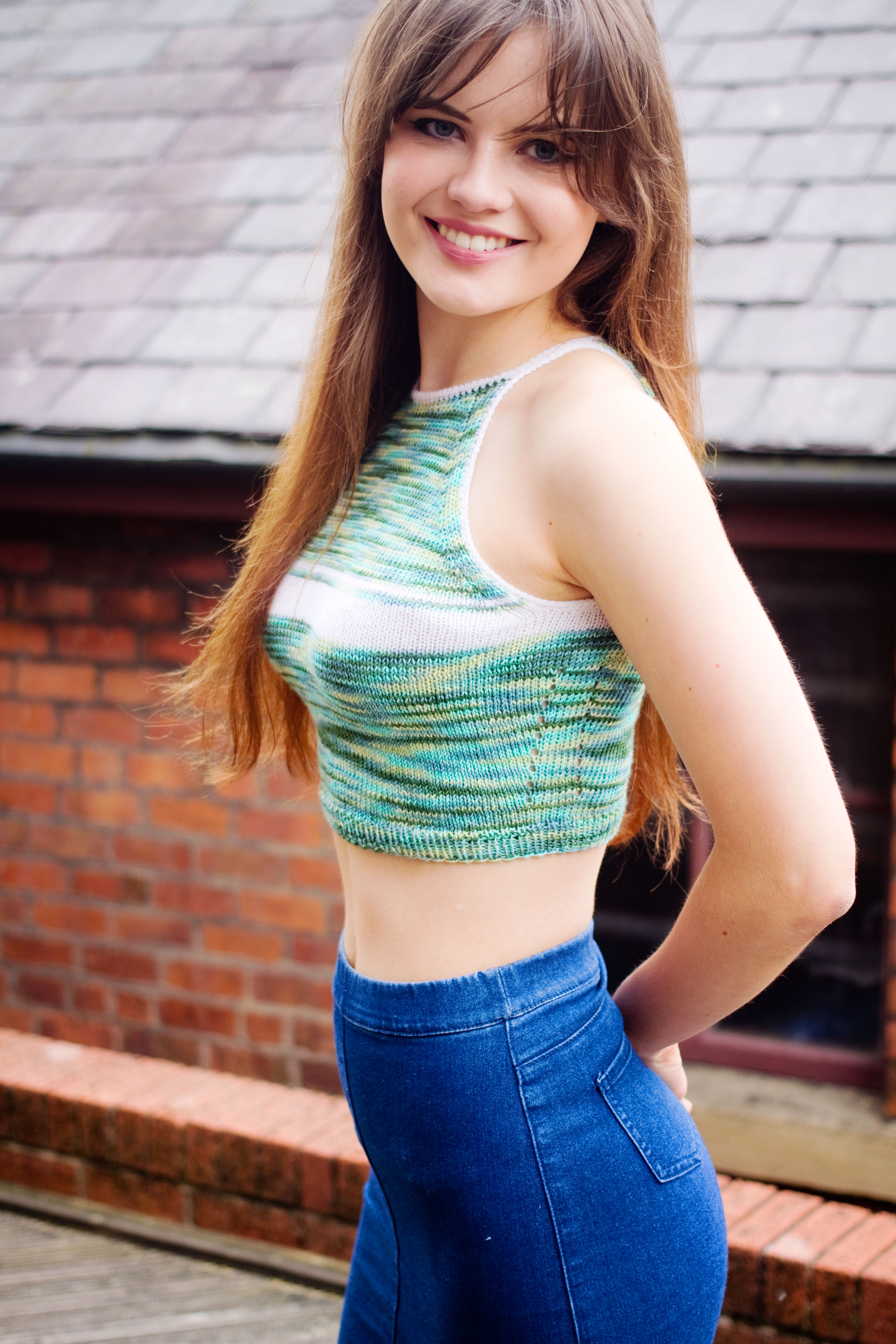 Smiling girl wearing handknit green and white cropped top and denim midi skirt