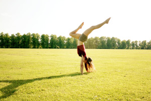 Teen blogger Lily Kate France doing handstand in park on sunny day