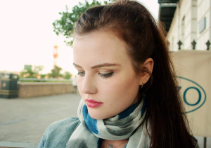 Girl with tied back brunette ponytail and wearing blue and white scarf