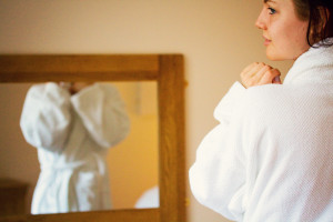 Girl wearing fluffy white robe loking in mirror