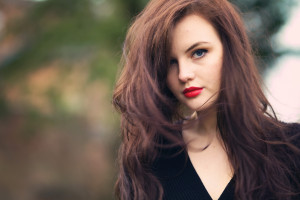 Teen girl with messy windblown long brunette hair and red lipstick