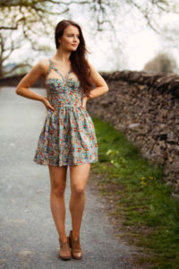 Girl wearing floral print dress walking down country lane