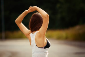Fitness outfit. Girl raising arms above head