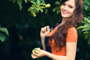 Smiling teen with handful of small apples