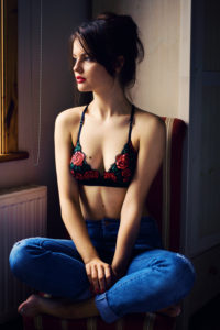 Girl wearing black and red bra and jeans and sitting cross-legged