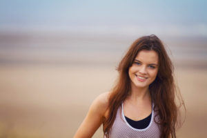 Smiling brunette girl. Beach background.