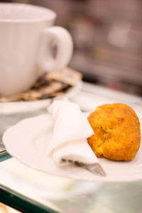 Baked snack on white plate with white napkin. White coffee cup