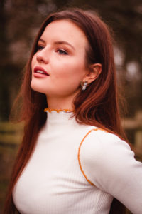 Female model wearing high neck top and silver earrings