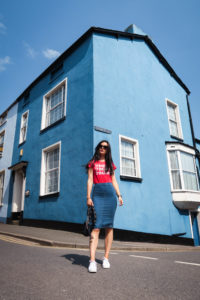 Young woman stood in front of blue painted corner house