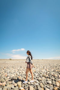 Girl walking on stoney beach Walney Island Cumbria
