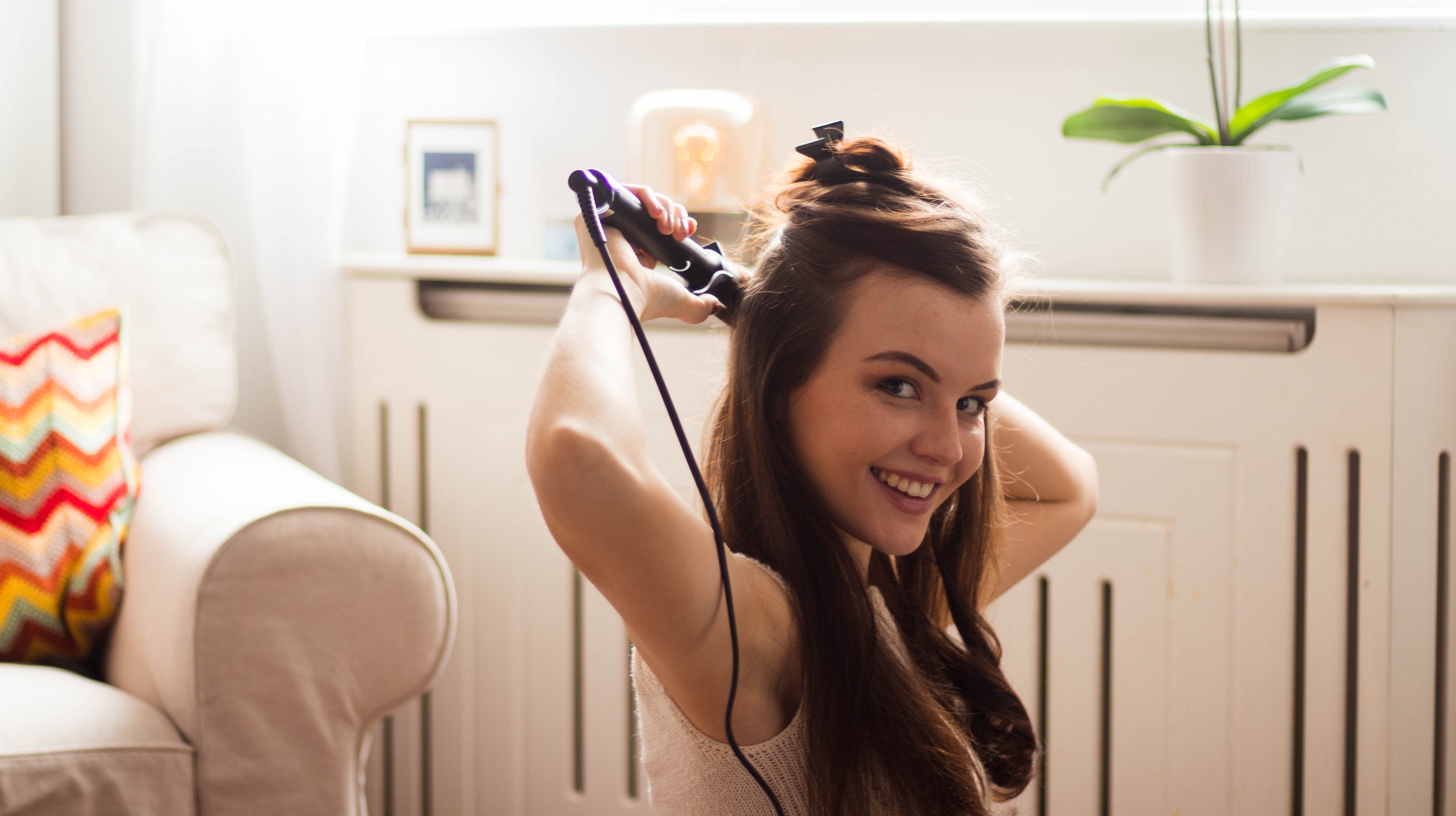 Young woman curling hair with GHD curling wand